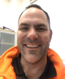 Head shot of Adam Walters, white male wearing an orange 